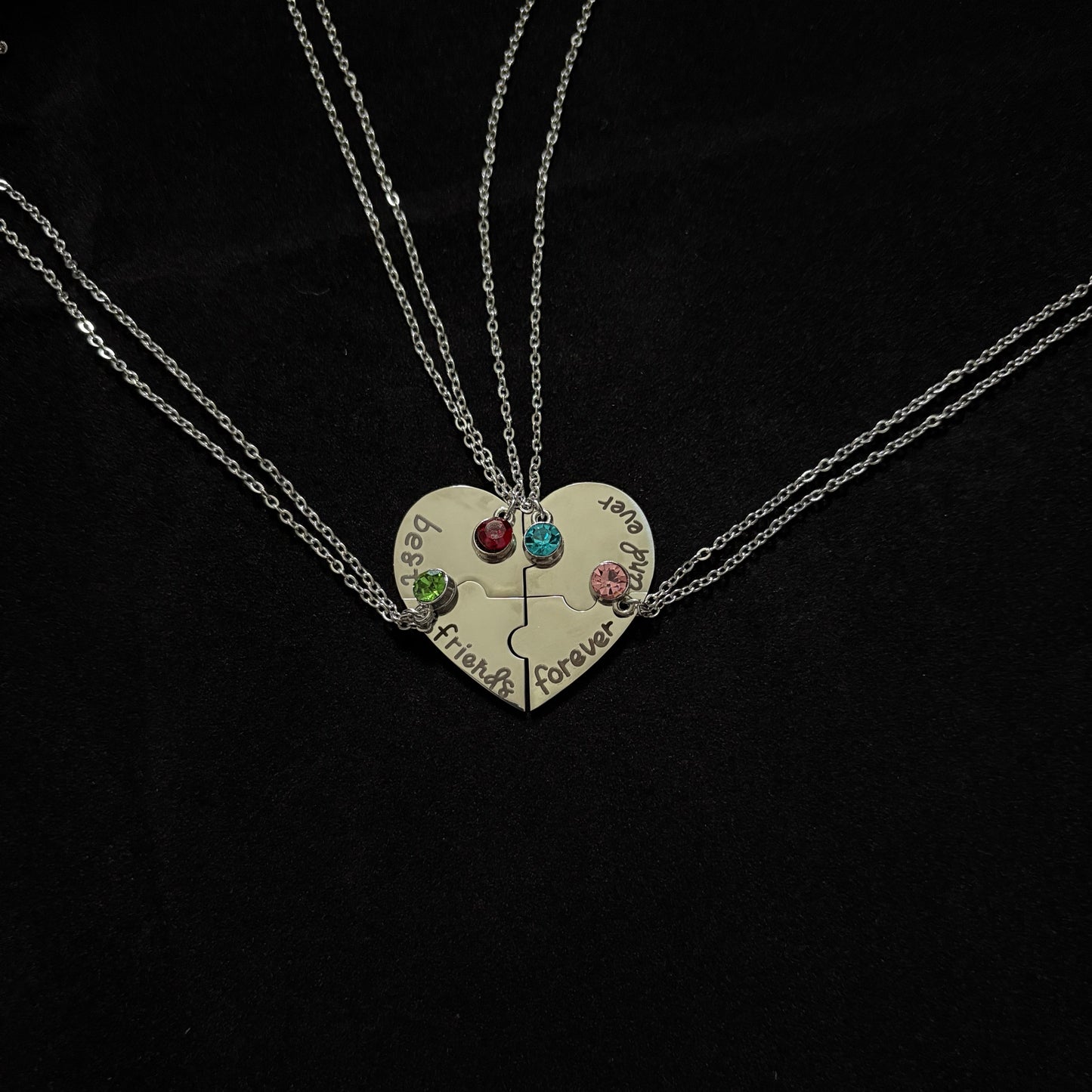 Necklace with a heart-shaped tag featuring three colored stones on a black background