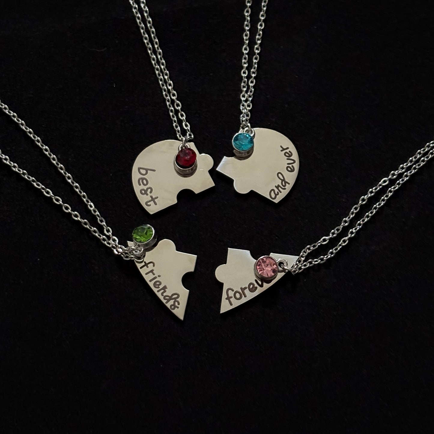 Two puzzle piece necklaces with engraved names on a black background