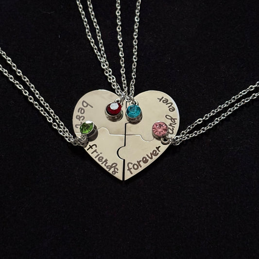 Heart-shaped pendant with engraved text and colorful gemstones on a black background