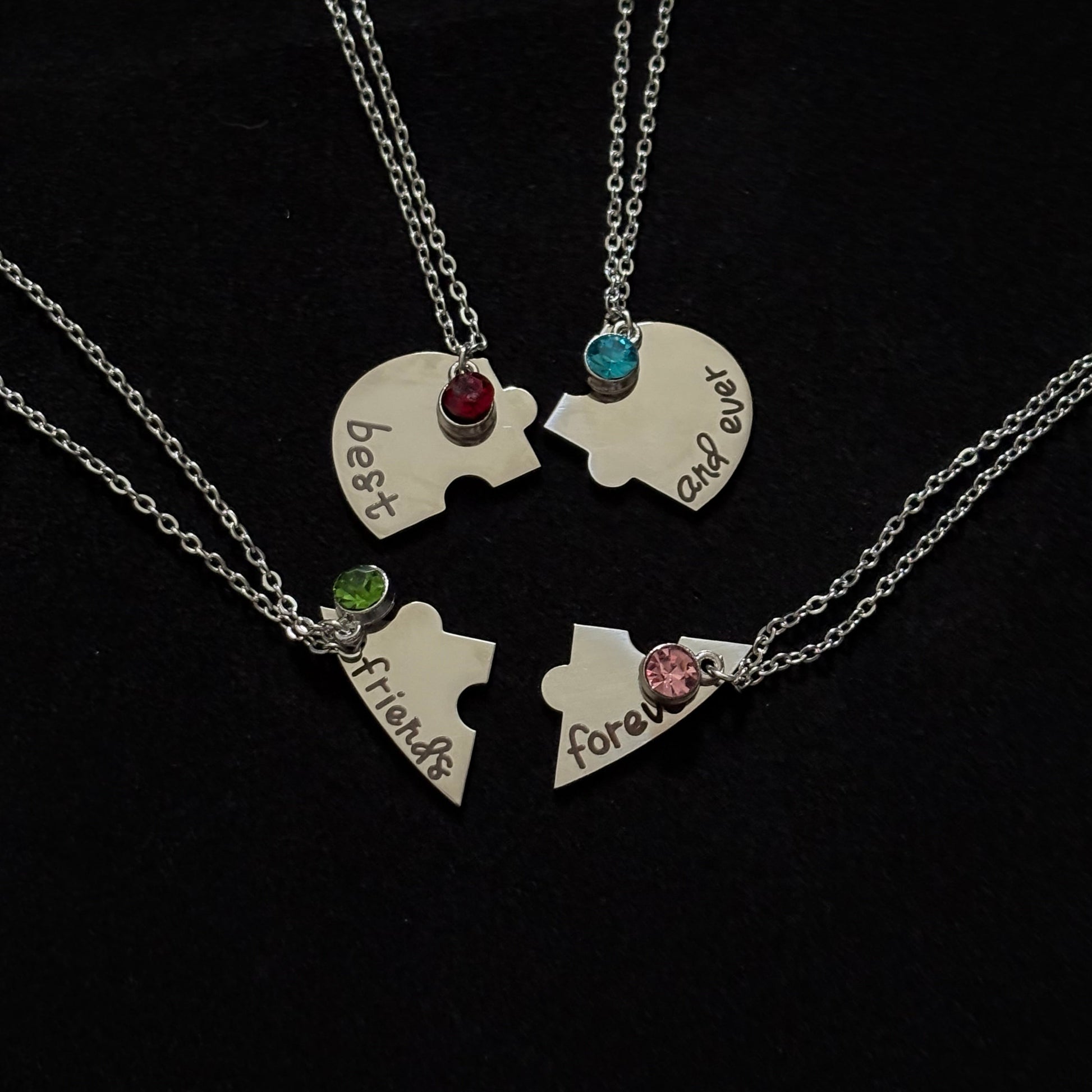 Two puzzle piece necklaces with engraved names on a black background