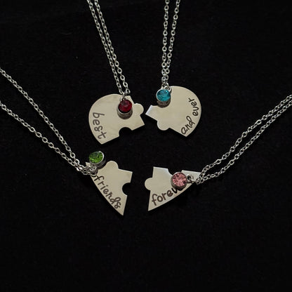 Two puzzle piece necklaces with engraved names on a black background